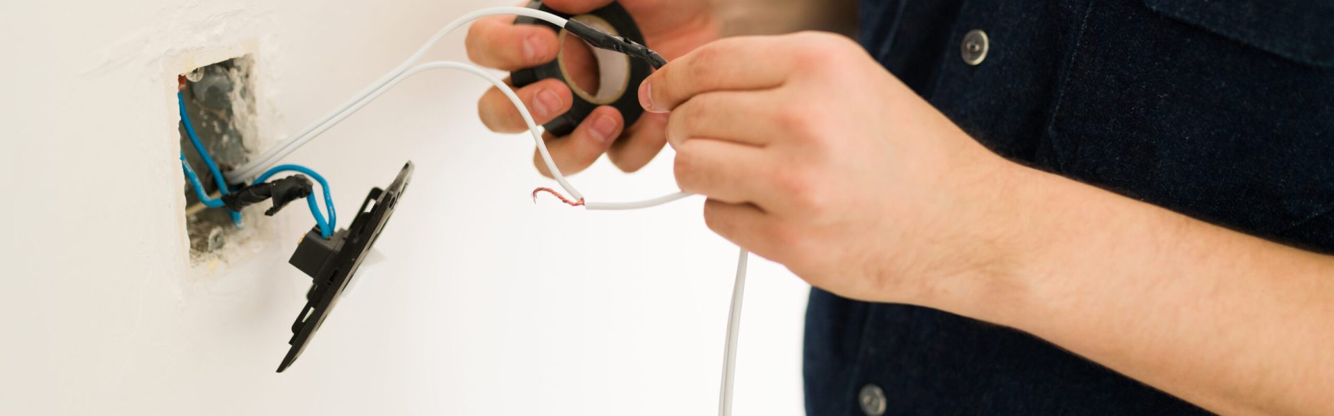 Close up of the hands of a young man hands repairing the broken switch and doing home renovations