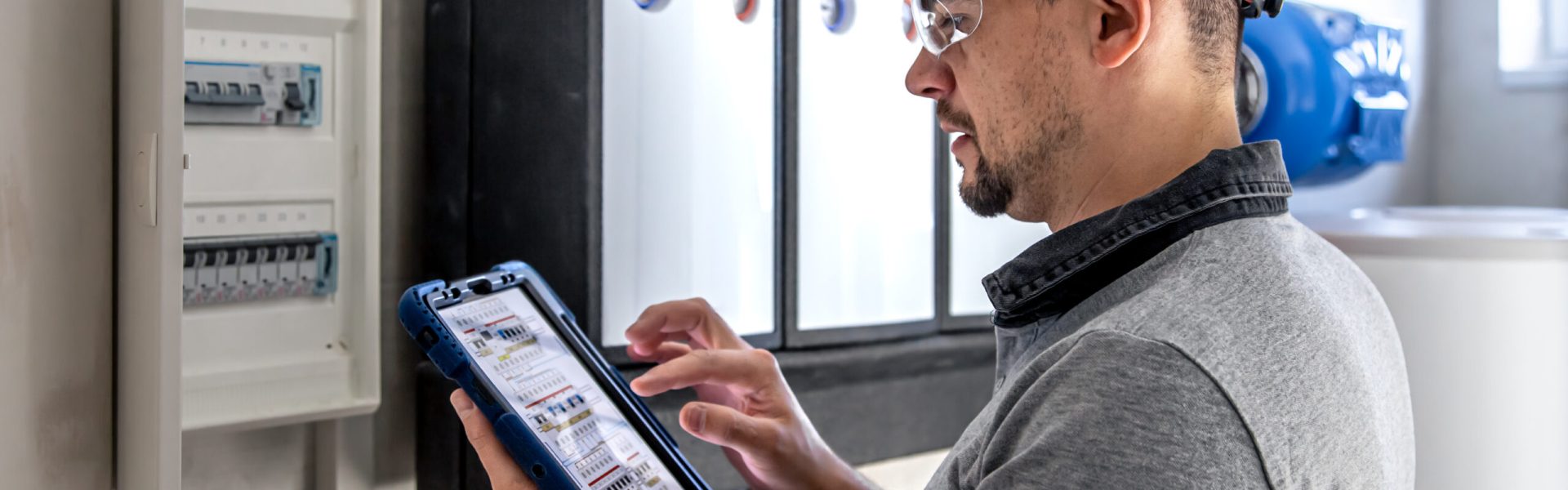 Electrical technician looking focused while working in a switchboard with fuses.