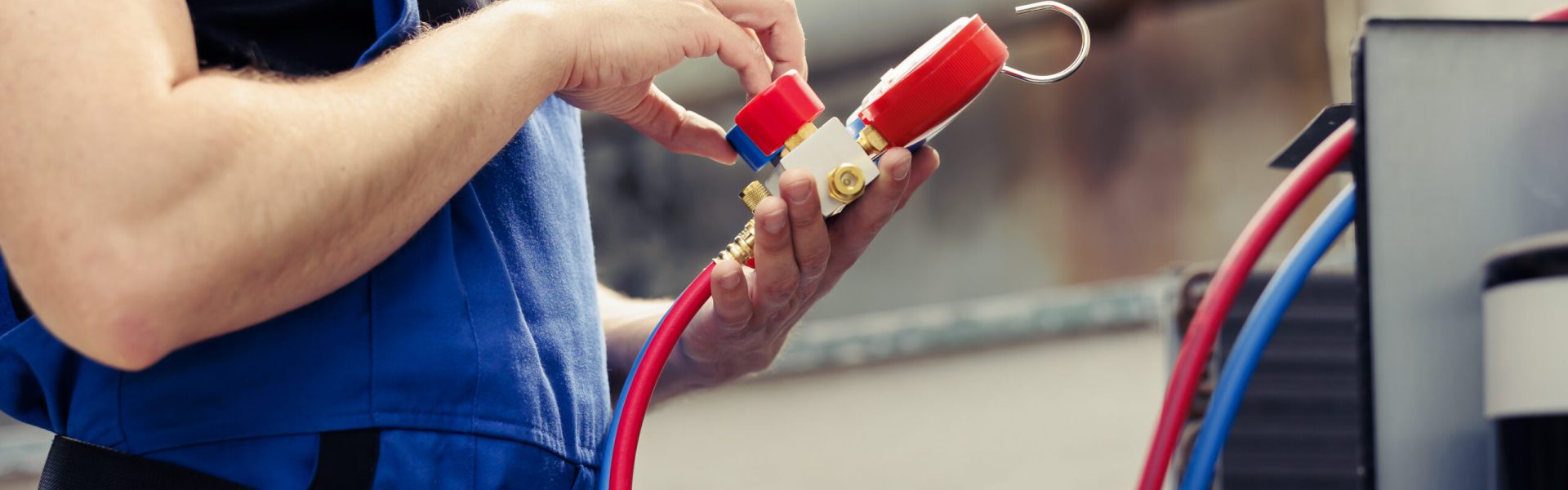 Experienced wireman doing annual air conditioner maintenance, assembling pressure measurement device before starting work. Licensed serviceman refilling cooling system refrigerant tank