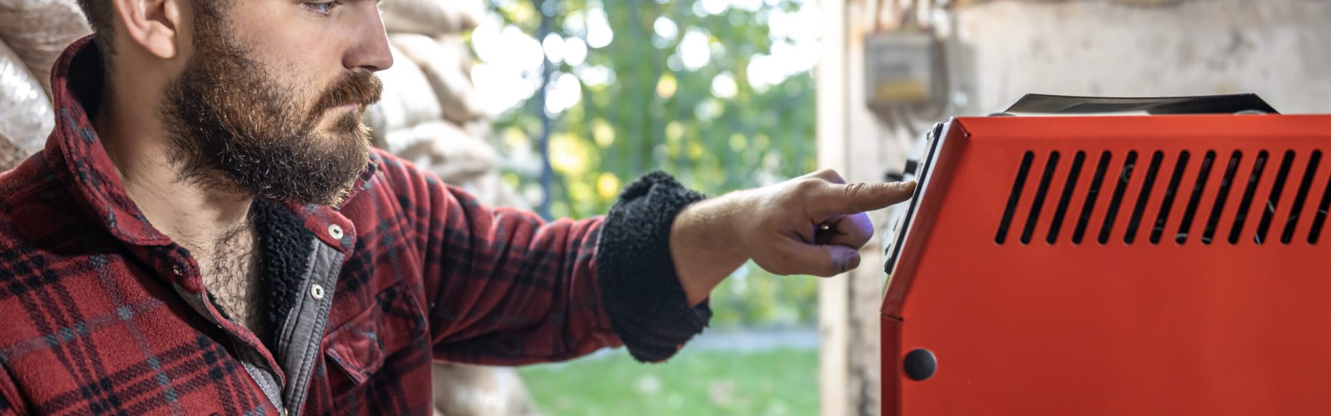 A young man in a room with a solid fuel boiler, working on biofuel, economical heating.